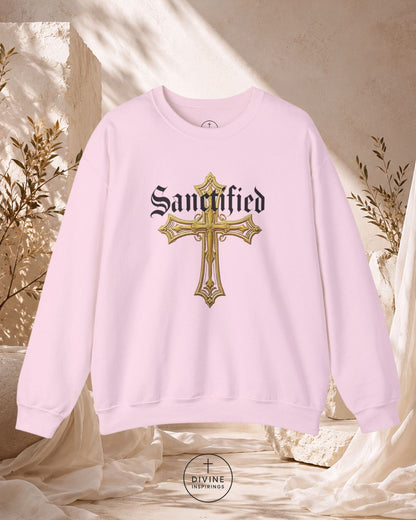 Pink sweatshirt with gold cross and 'Sanctified' text on a neutral background