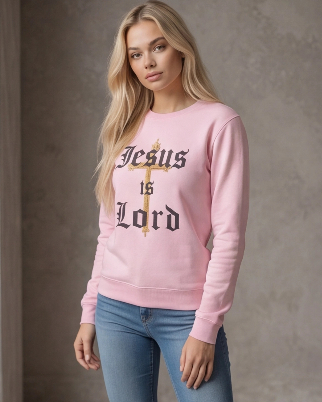 Woman wearing a pink sweatshirt with 'Jesus is Lord' text against a plain background