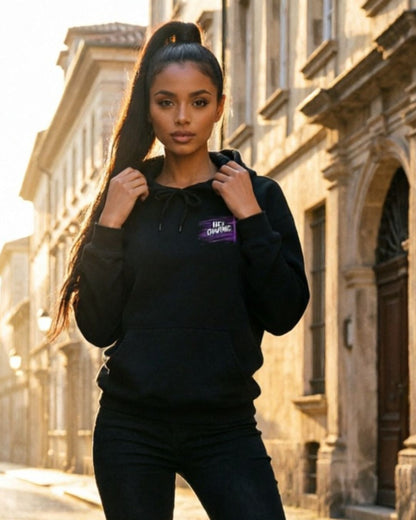 Woman wearing a black hoodie with a visible brand logo in an urban setting