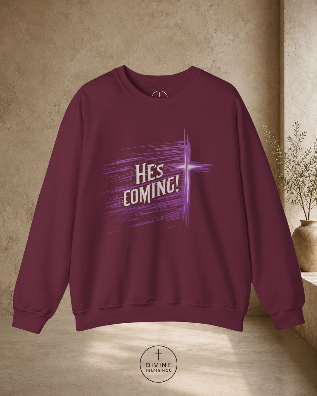 Maroon sweatshirt with 'HE'S COMING!' text on a beige background