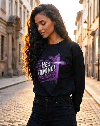 Woman wearing a black sweatshirt with 'HE'S COMING!' text on a cobblestone street.