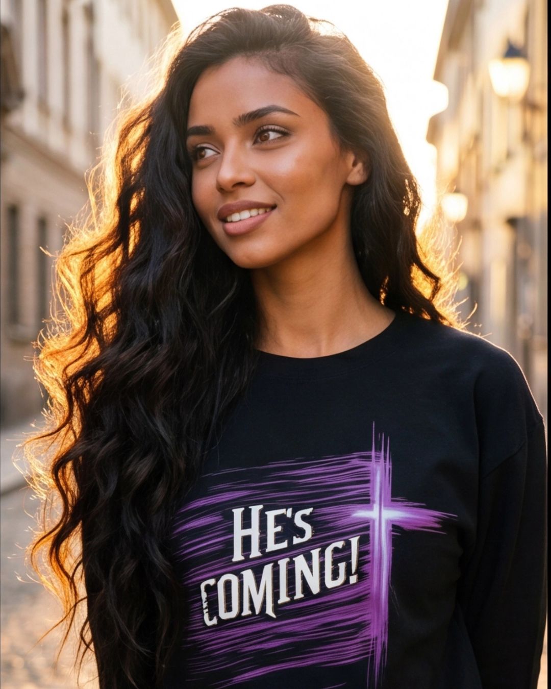 Woman wearing a black sweatshirt with 'HE'S COMING!' text in a city setting