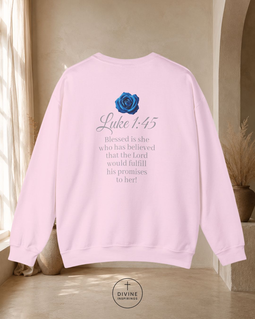 Pink sweatshirt with a blue rose and text on the back, displayed indoors.