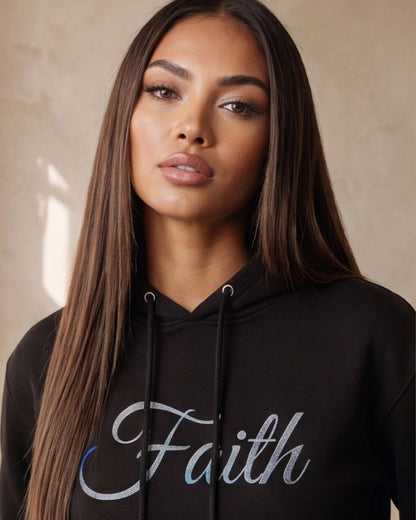 Woman wearing a black hoodie with 'Faith' text on a beige background