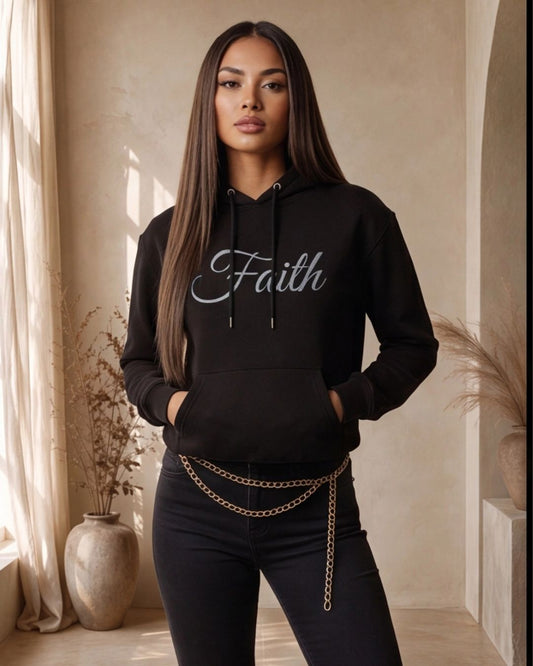 Woman wearing a black hoodie with 'Faith' text in a room with curtains and plants.