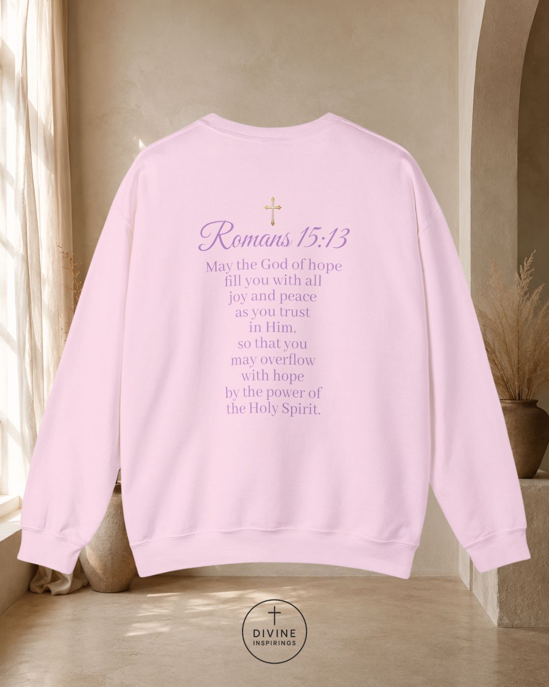 Pink sweatshirt with 'Romans 15:13' text in a home setting