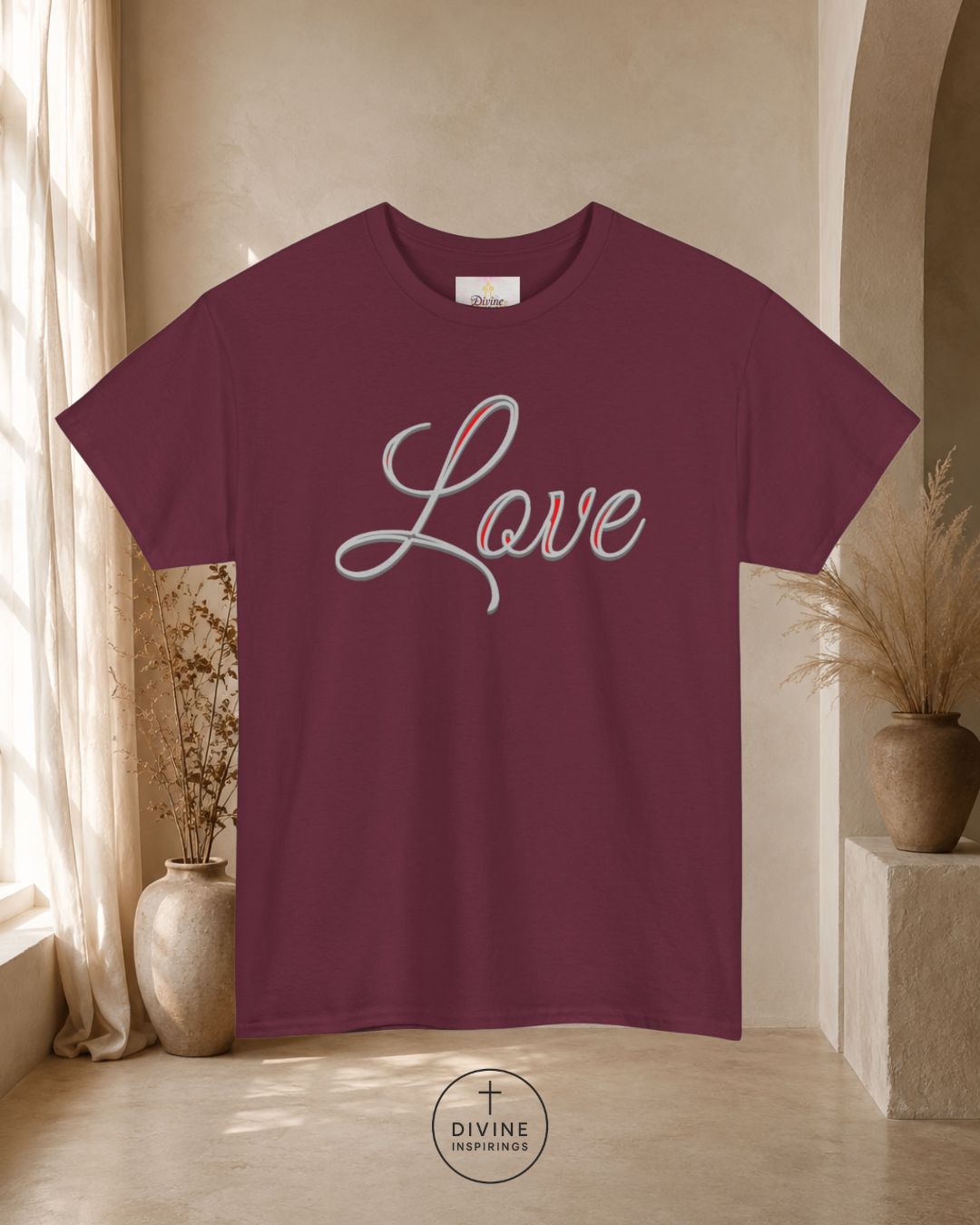 Maroon t-shirt with 'Love' printed on it in a room with decorative plants and a neutral wall.