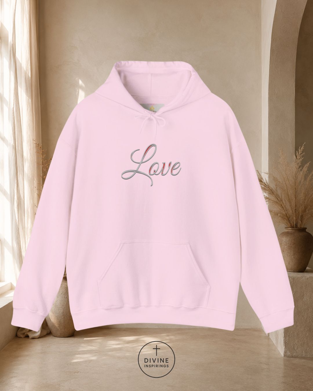 Pink hoodie with 'Love' text on a neutral background