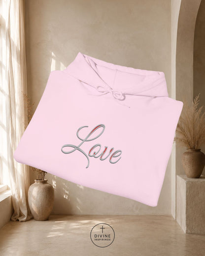 Pink blanket with 'Love' embroidery in a room with curtains and a vase.