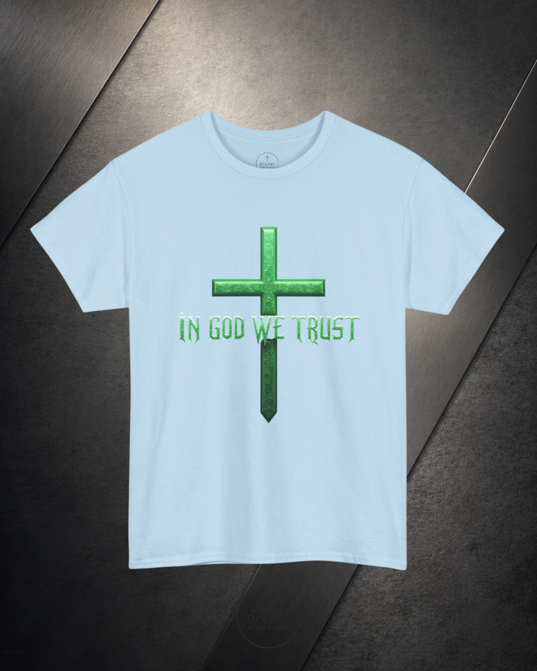 Light blue t-shirt with green cross and 'IN GOD WE TRUST' text on a dark surface