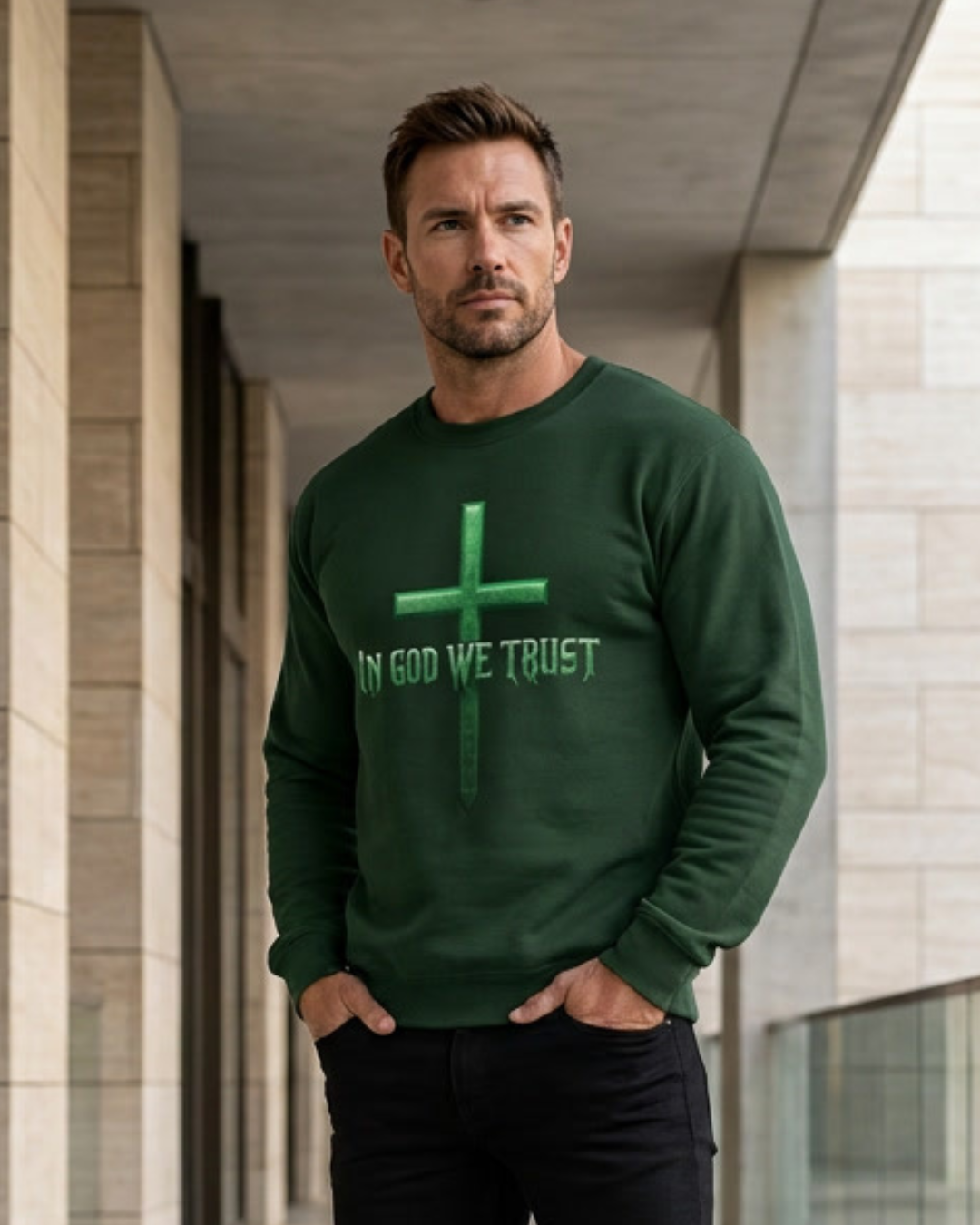 Man wearing a green sweatshirt with 'In God We Trust' text and cross symbol outdoors.