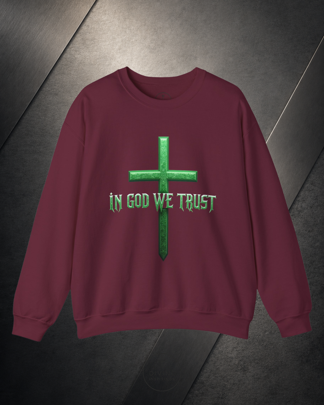 Maroon sweatshirt with green cross and 'In God We Trust' text on a dark metallic surface
