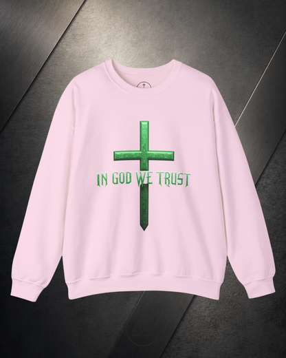 Pink sweatshirt with green cross and 'IN GOD WE TRUST' text on a dark surface