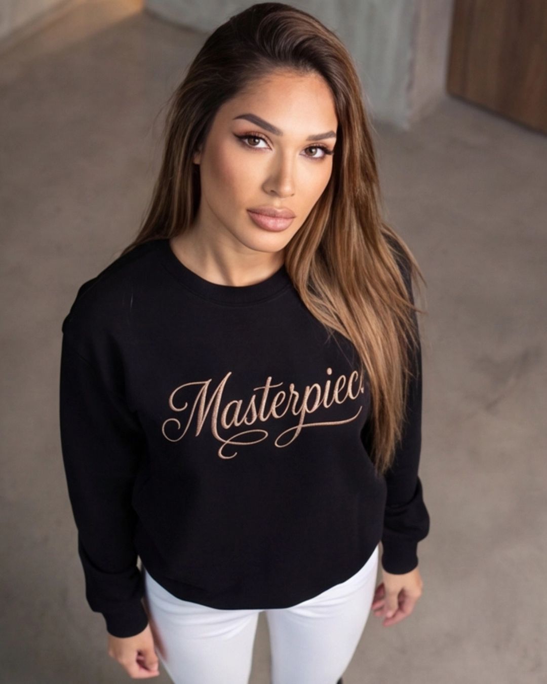 Woman wearing a black sweatshirt with 'Masterpiece' text against a neutral background