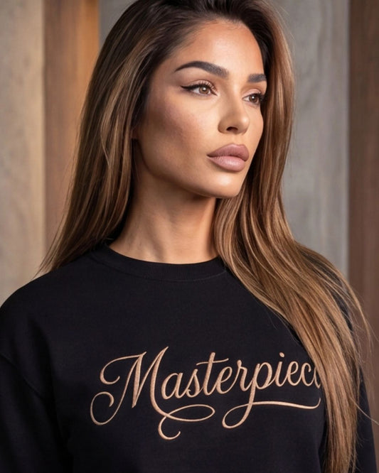 Woman wearing a black sweatshirt with 'Masterpiece' text