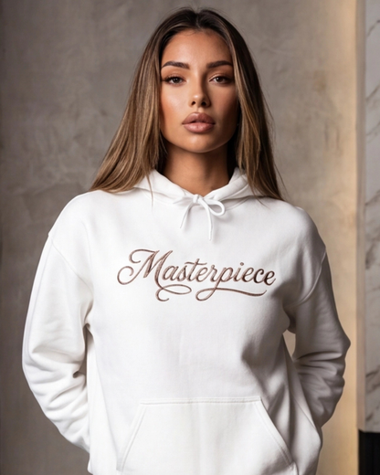 Woman wearing a white hoodie with 'Masterpiece' text against a neutral background