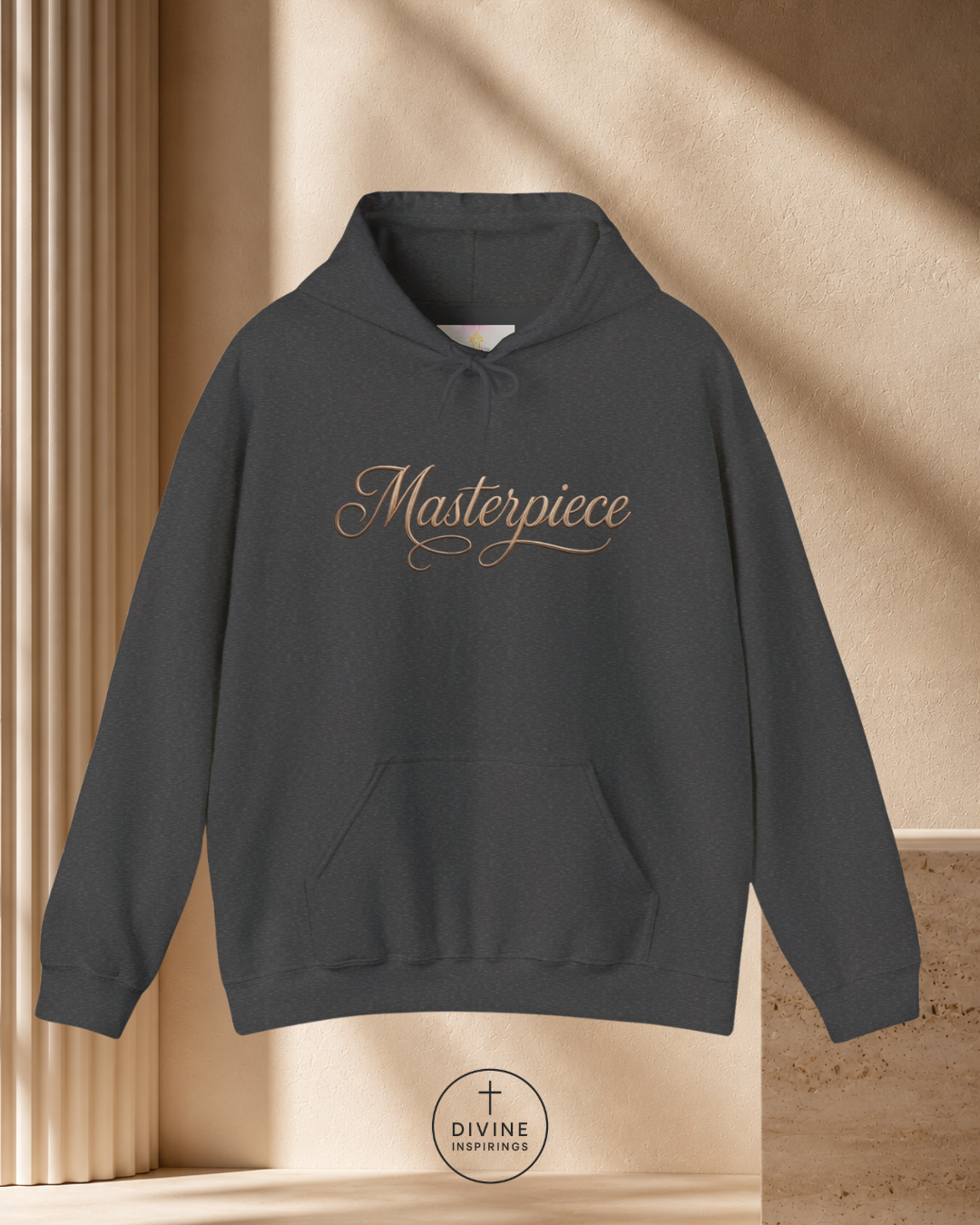 Dark gray hoodie with 'Masterpiece' text on a beige background