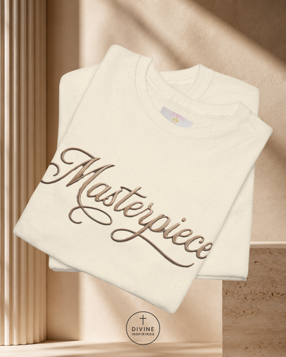 Folded white sweatshirt with 'Masterpiece' text on a beige background