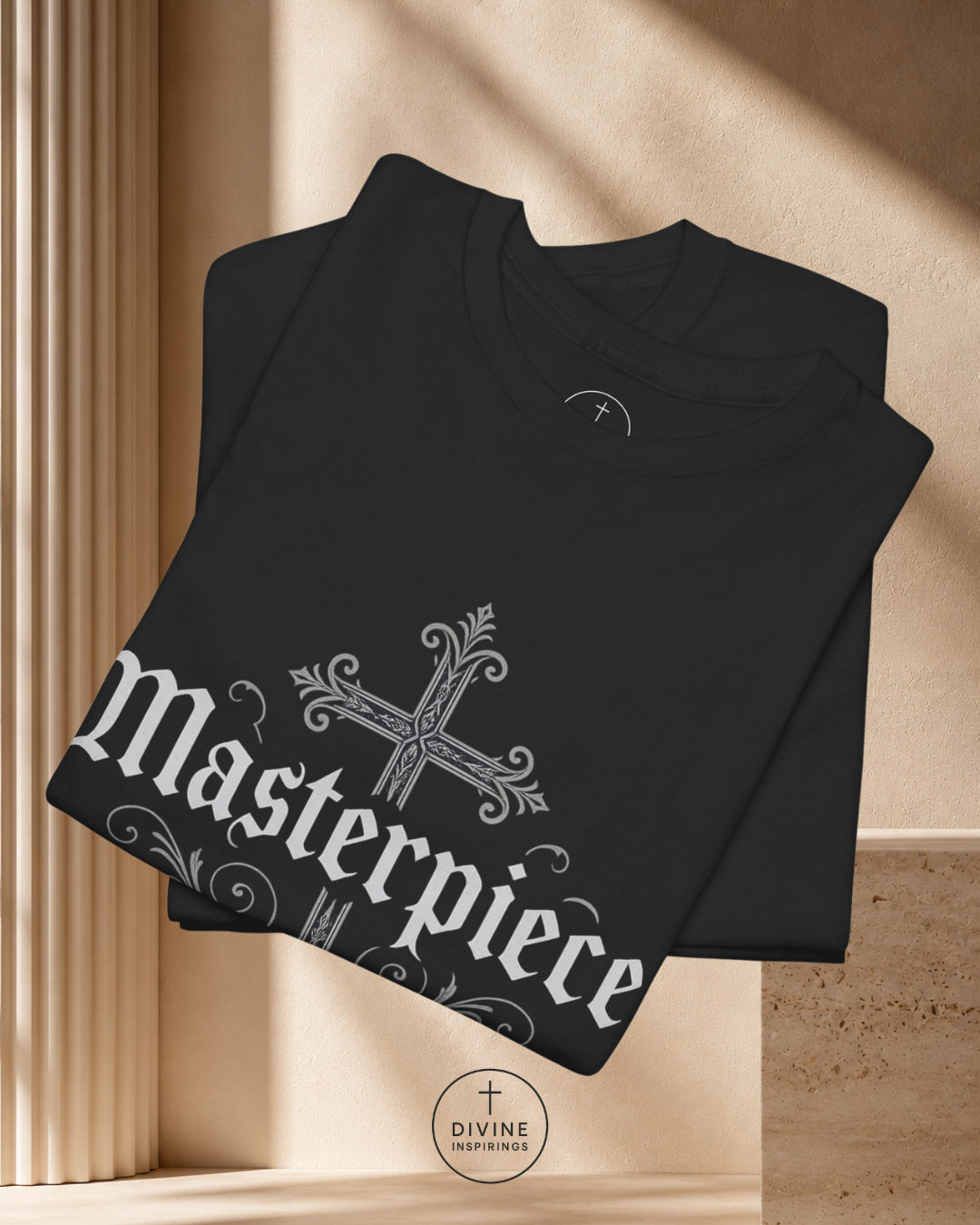 Folded black shirt with 'Masterpiece' design on a beige background