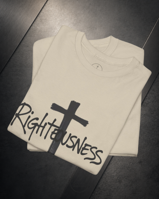 Folded beige sweatshirt with a black cross and 'Righteousness' text on a dark surface