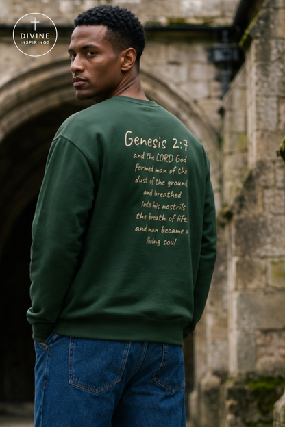 A man wearing a dark green crewneck sweatshirt with white printed scripture text on the back, standing outdoors in front of a stone archway. The Divine Inspirings logo is visible in the top left corner.