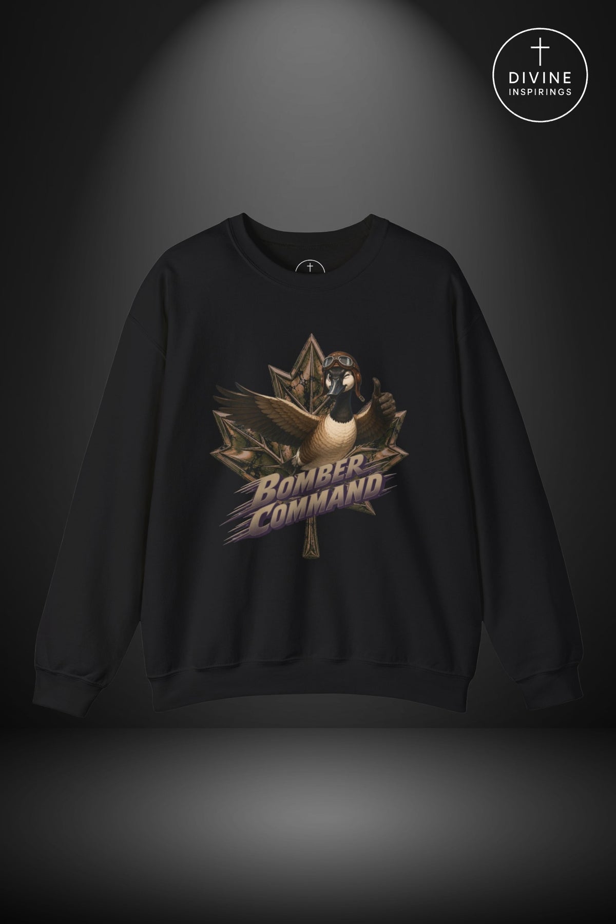 A black crewneck sweatshirt featuring a graphic of a goose inside a maple leaf with the text 'Bomber Command' in stylized lettering. The sweatshirt is displayed against a dark gray background with a spotlight effect, and a 'Divine Inspirings' logo is visible in the top right corner.