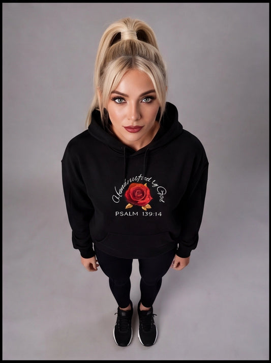 Person wearing a black hoodie with a red rose design and text on a gray background