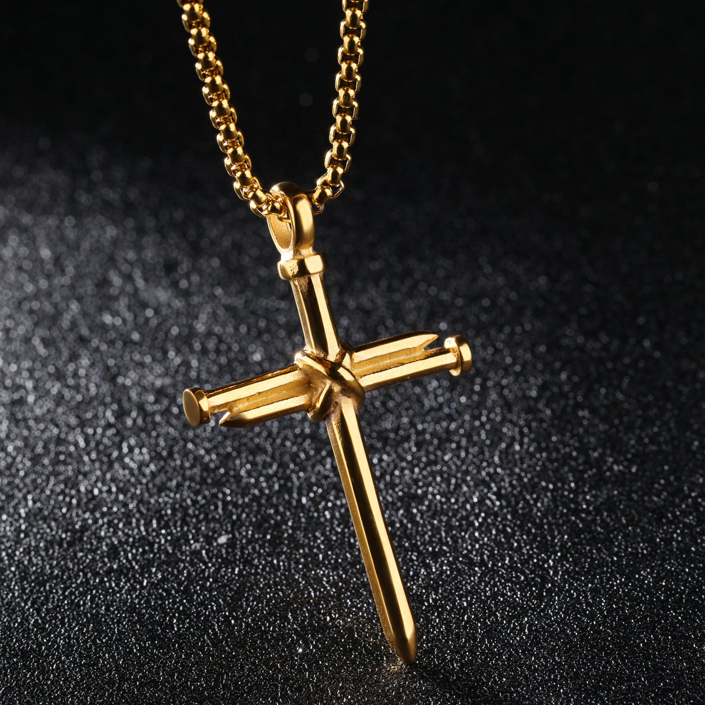 Gold cross necklace with a nail detail on a black textured background
