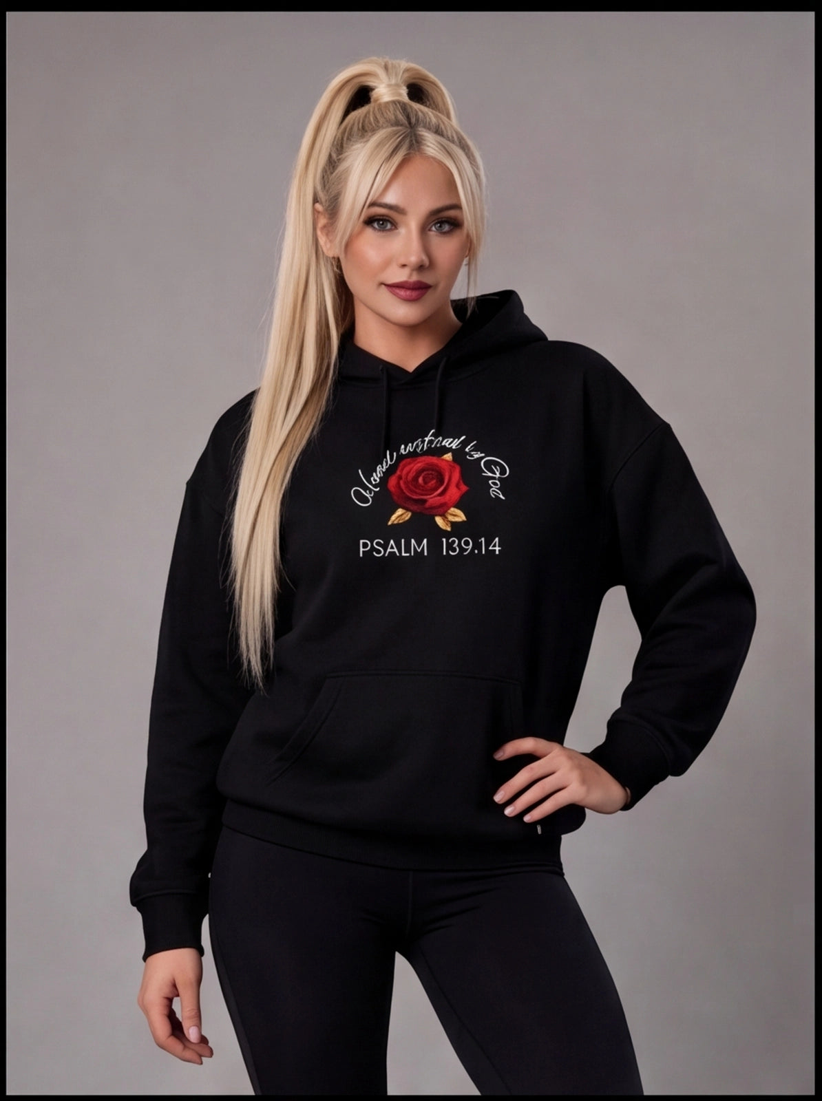 Woman wearing a black hoodie with a red rose design and Psalm 139:14 text on a gray background