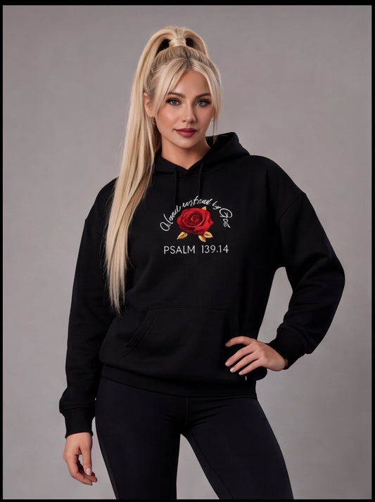 Woman wearing a black hoodie with a red rose design and Psalm 139:14 text on a gray background