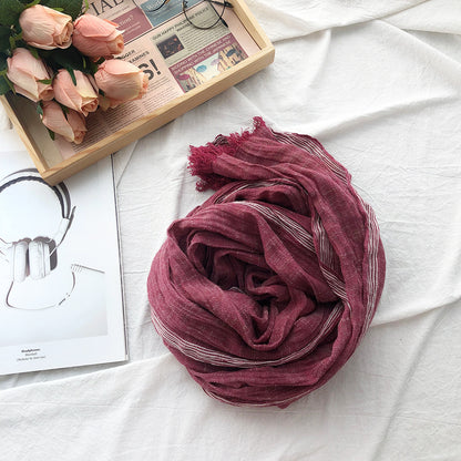 Purple scarf on a white surface with a tray of pink roses and a magazine.