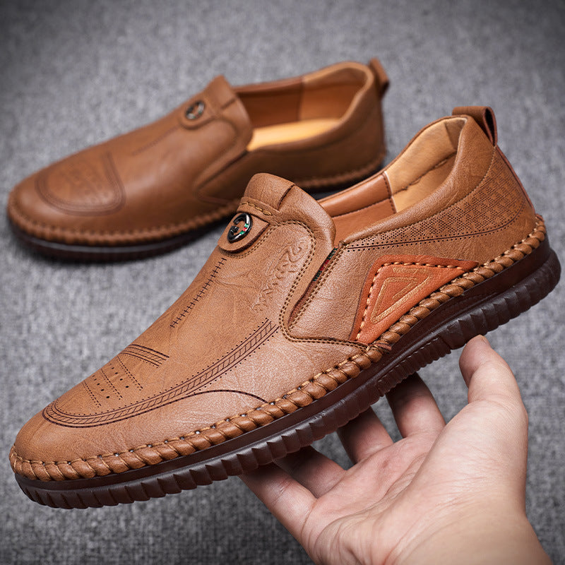 Brown leather shoes held by a hand on a gray background
