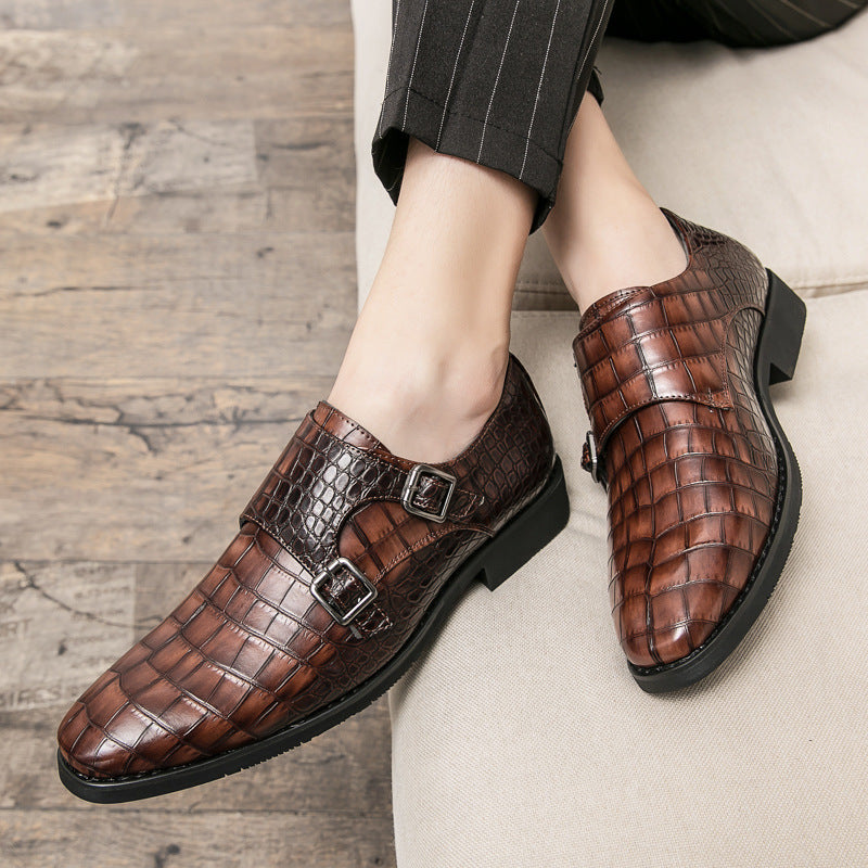 Brown leather shoes with crocodile pattern worn by a person on a wooden floor.