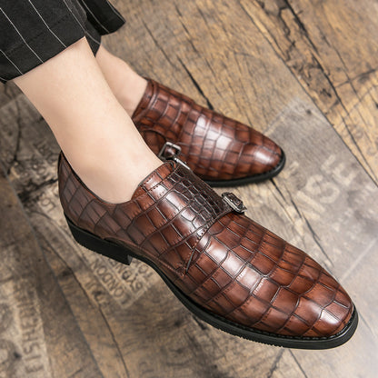 Brown leather shoes with crocodile pattern worn on a wooden floor