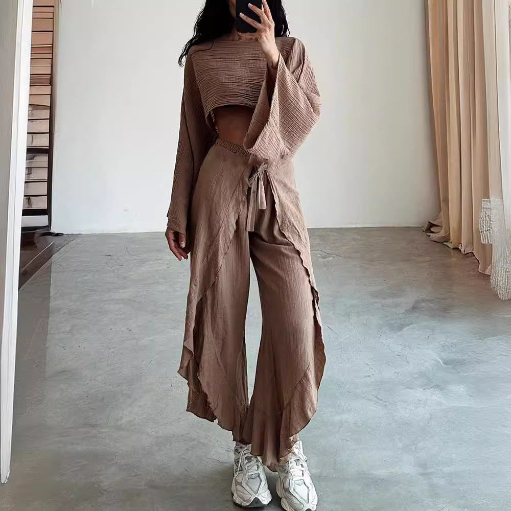 Person wearing a brown outfit with wide-leg pants in a minimalistic room.