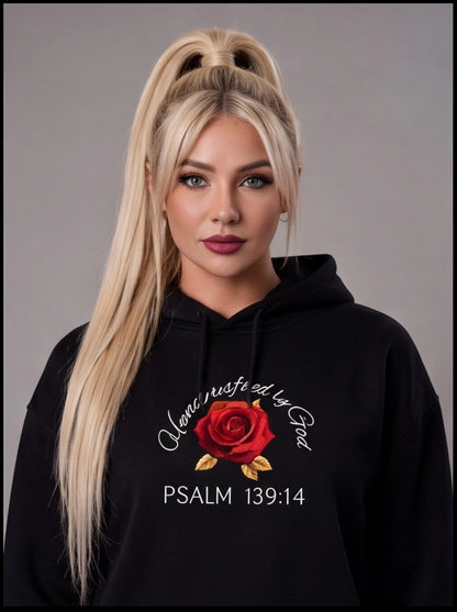 Woman wearing a black hoodie with a red rose design and text on a gray background