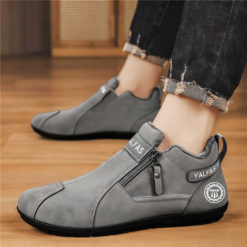 Gray ankle boots with a brand logo worn indoors on a wooden floor.