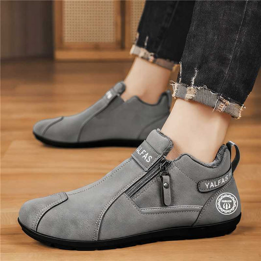 Gray ankle boots with a brand logo worn indoors on a wooden floor.