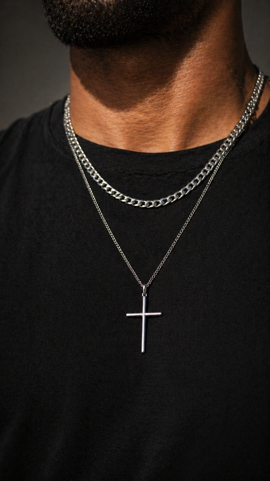Silver chain necklace with a cross pendant on a black shirt