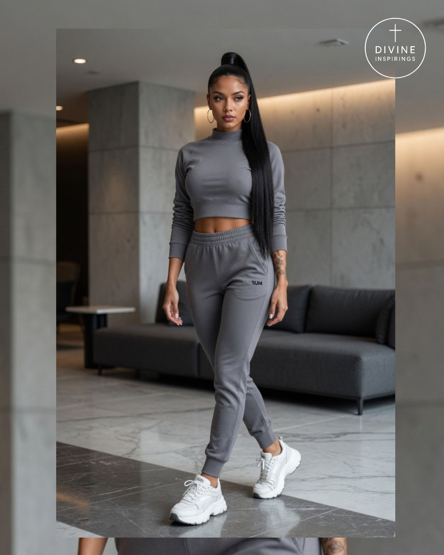 A woman modeling a matching gray two-piece activewear set consisting of a long-sleeve crop top and jogger pants, styled with white sneakers in a modern indoor setting.