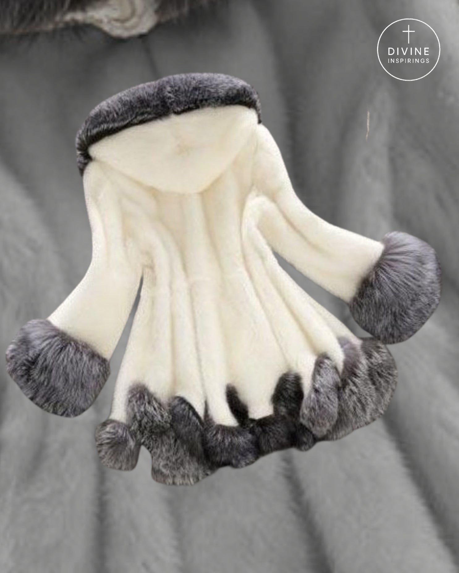 A cream-colored faux fur hooded garment with gray faux fur trim on the hood, cuffs, and hem, displayed against a gray textured fabric background. A circular 'DIVINE INSPIRINGS' logo is visible in the top right corner.