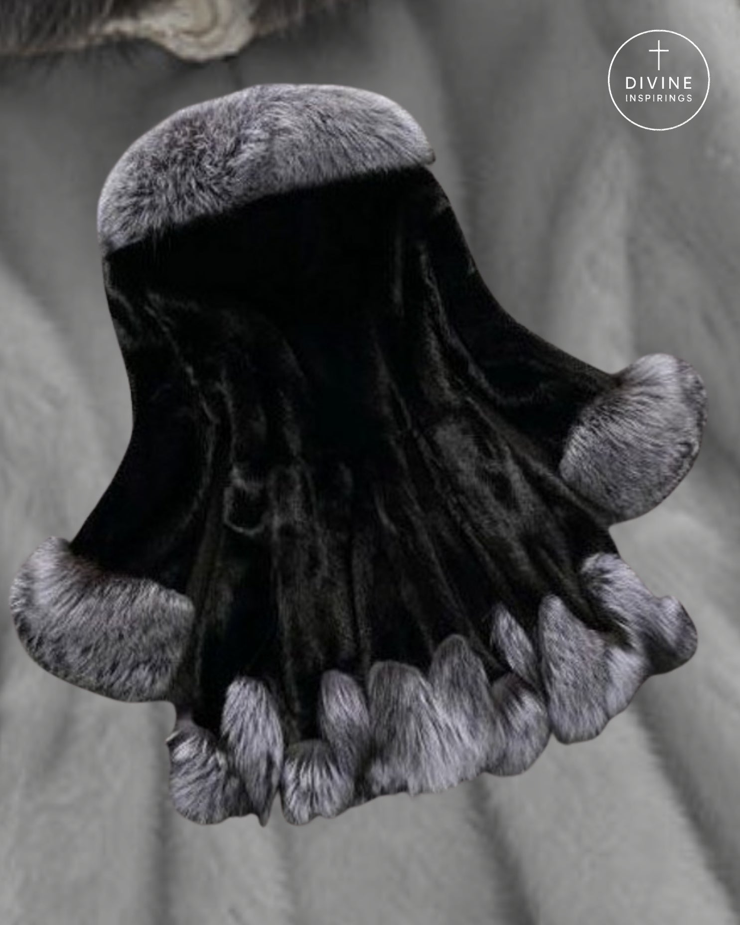 A black velvet hood or cape with plush gray fur trim at the top, sides, and bottom hem, displayed against a soft gray fabric background. A circular 'DIVINE INSPIRINGS' logo is visible in the upper right corner.