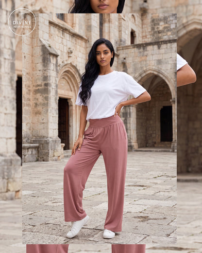 A woman stands in a stone courtyard wearing a white short-sleeve T-shirt and dusty rose wide-leg pants with white sneakers. The image includes a vertical mirror reflection on the right side and a circular 'Divine Inspirings' logo in the top-left corner.