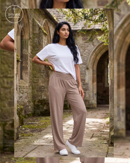 A woman stands in a stone courtyard wearing a white short-sleeve t-shirt and high-waisted, wide-leg taupe pants with white sneakers. The image has a vertical mirror reflection on the left and a brand watermark 'Divine Inspirings' in the upper left.