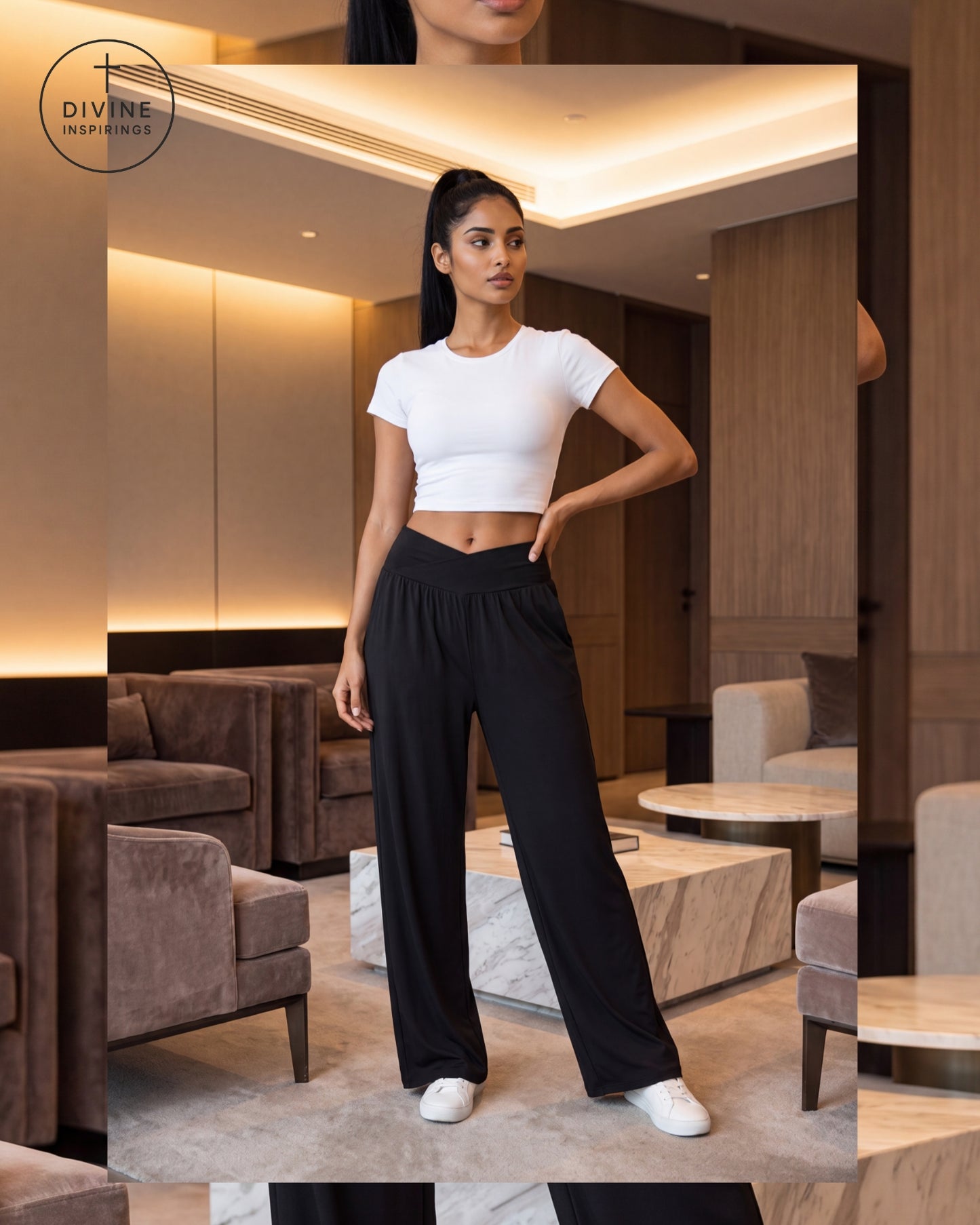 A woman modeling a white short-sleeve crop top and black wide-leg pants in a modern, warmly lit living room. The Divine Inspirings logo is visible in the top left corner.