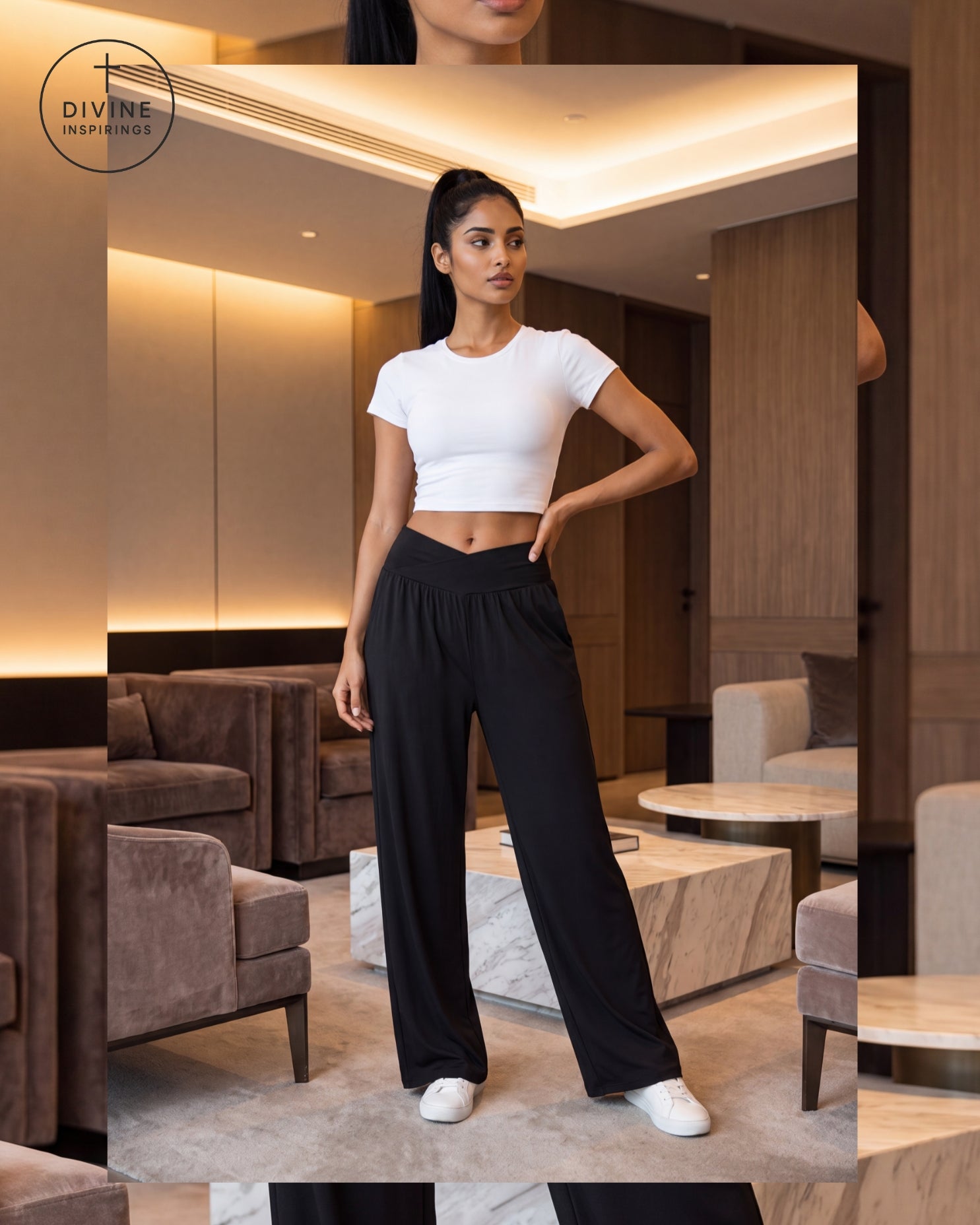 A woman modeling a white short-sleeve crop top and black wide-leg pants in a modern, warmly lit living room. The Divine Inspirings logo is visible in the top left corner.