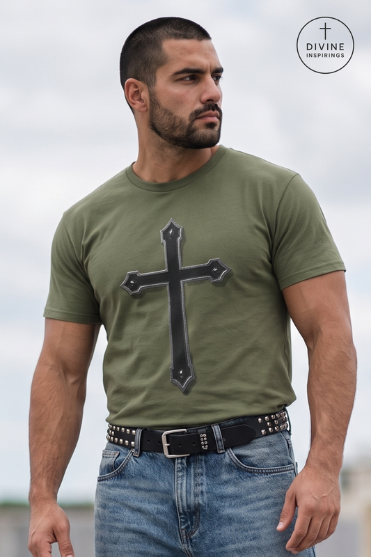 A muscular man wearing an olive green t-shirt with a large black cross graphic on the front, paired with blue jeans and a studded black belt. The background is a cloudy sky, and a circular 'DIVINE INSPIRINGS' logo is visible in the top right corner.