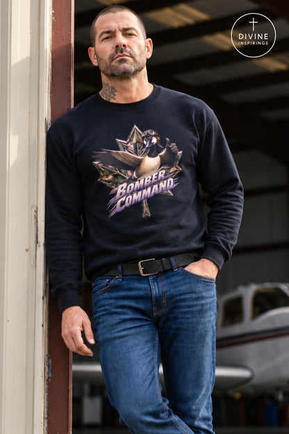 A man wearing a navy blue crewneck sweatshirt with a 'Bomber Command' bird graphic, paired with blue jeans, leaning against a doorway in front of an aircraft hangar. A 'Divine Inspirings' logo is visible in the top right corner.
