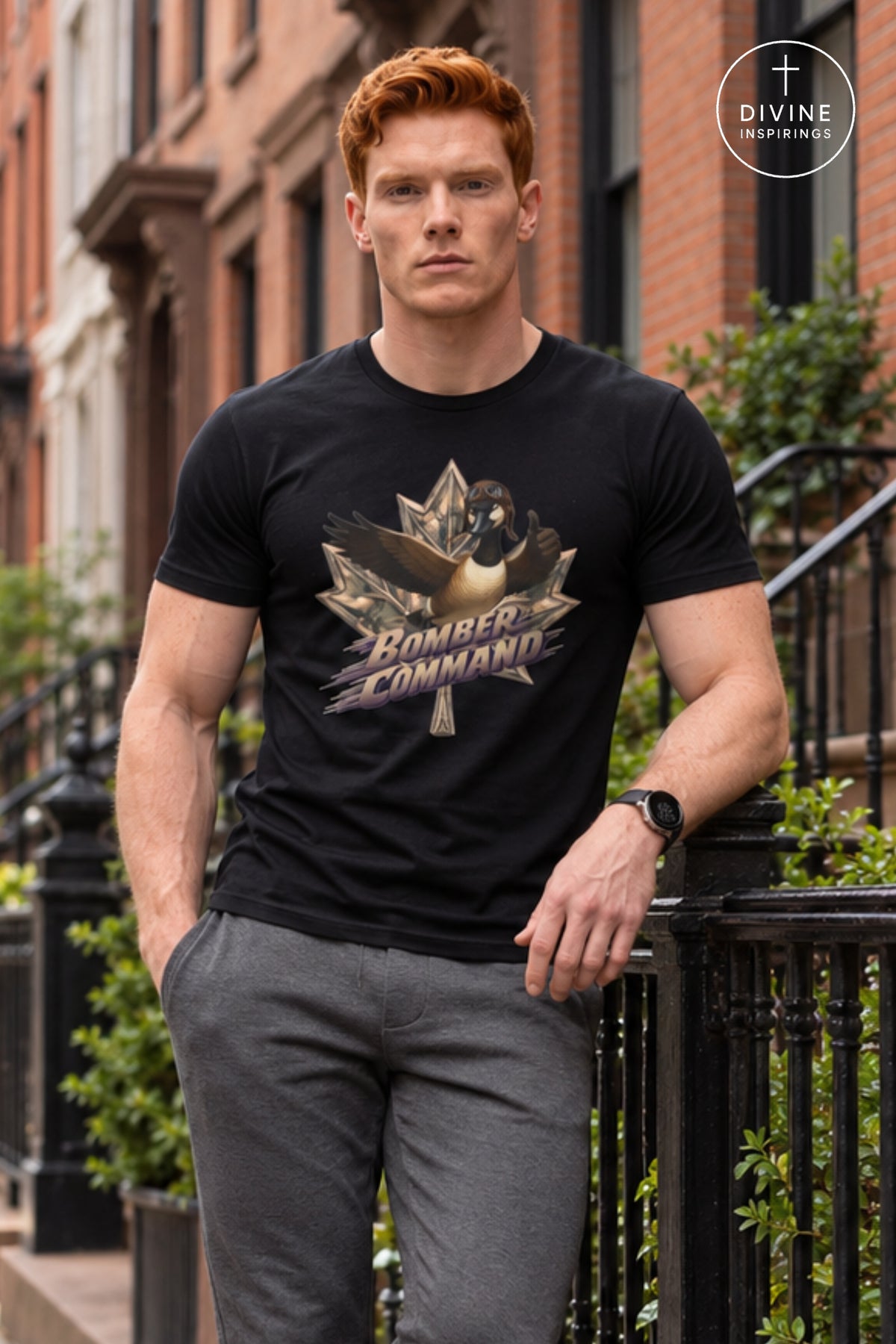 A man wearing a black graphic t-shirt with a bomber command maple leaf design, standing outdoors in front of brick townhouses. The Divine Inspirings brand logo is visible in the top right corner.