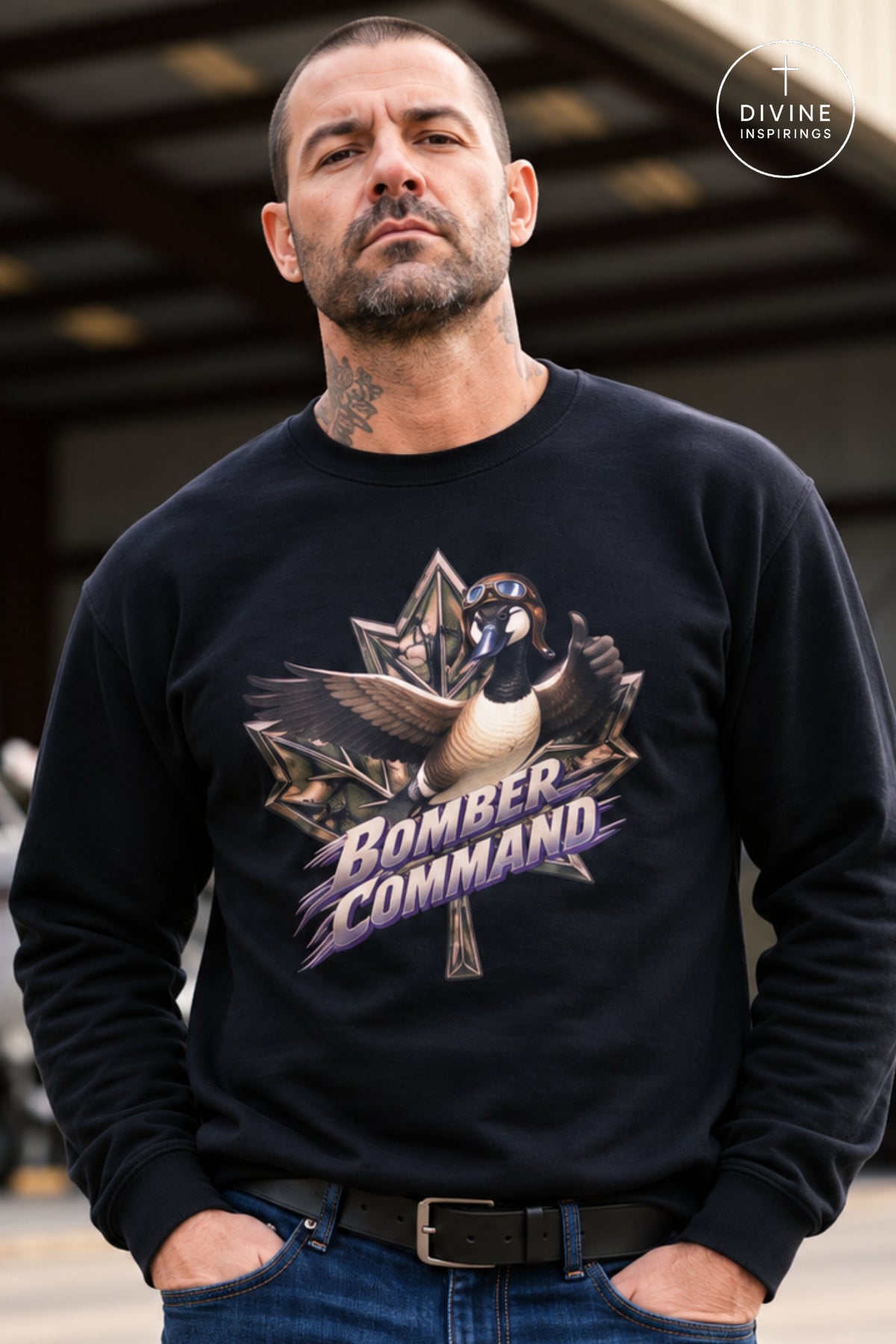 A man wearing a black crewneck sweatshirt with a graphic of a goose and the words 'Bomber Command' in purple and gold. The background is a blurred industrial setting.